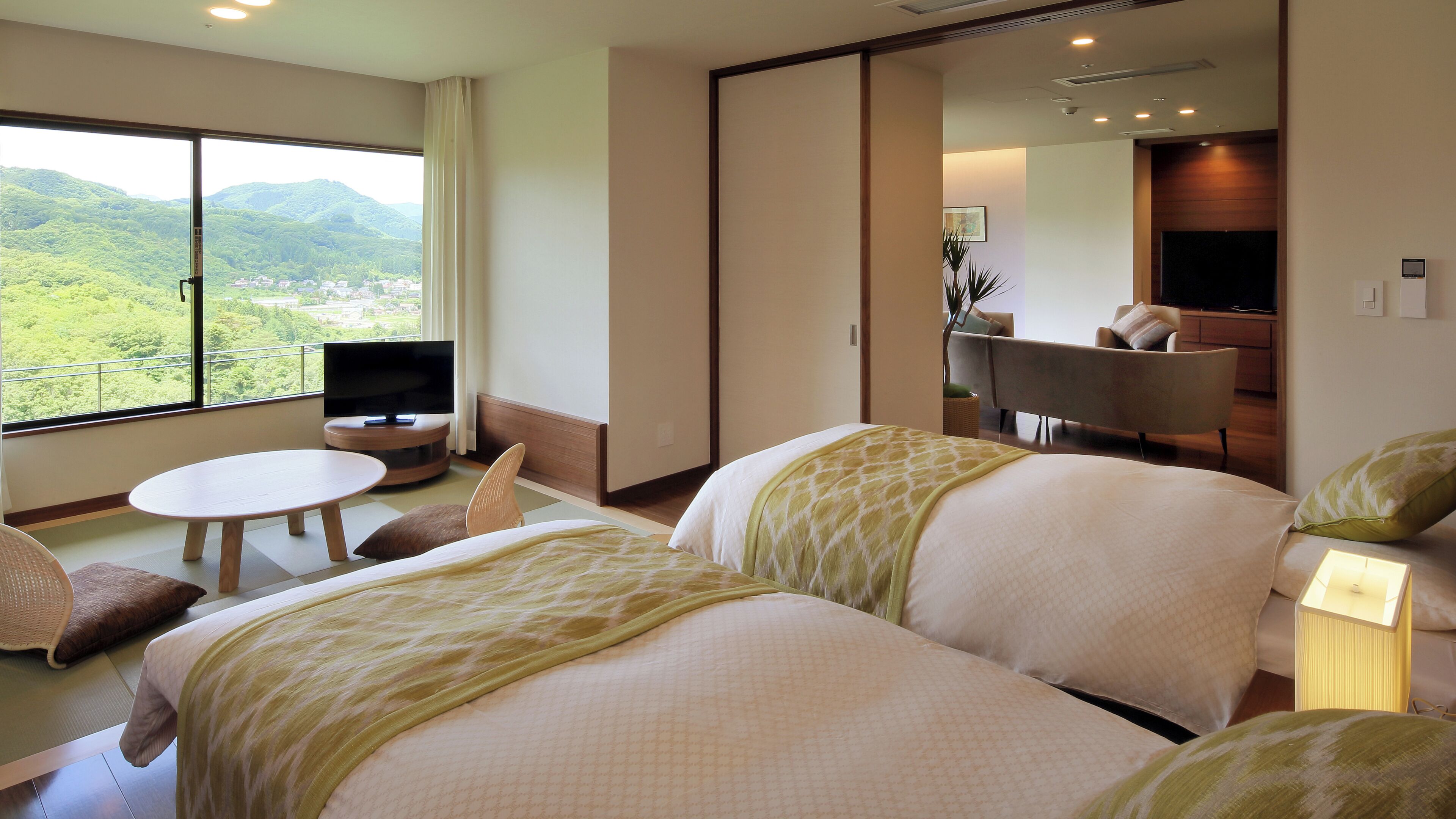 A hotel room with two beds, a TV, a small table, and a sofa.