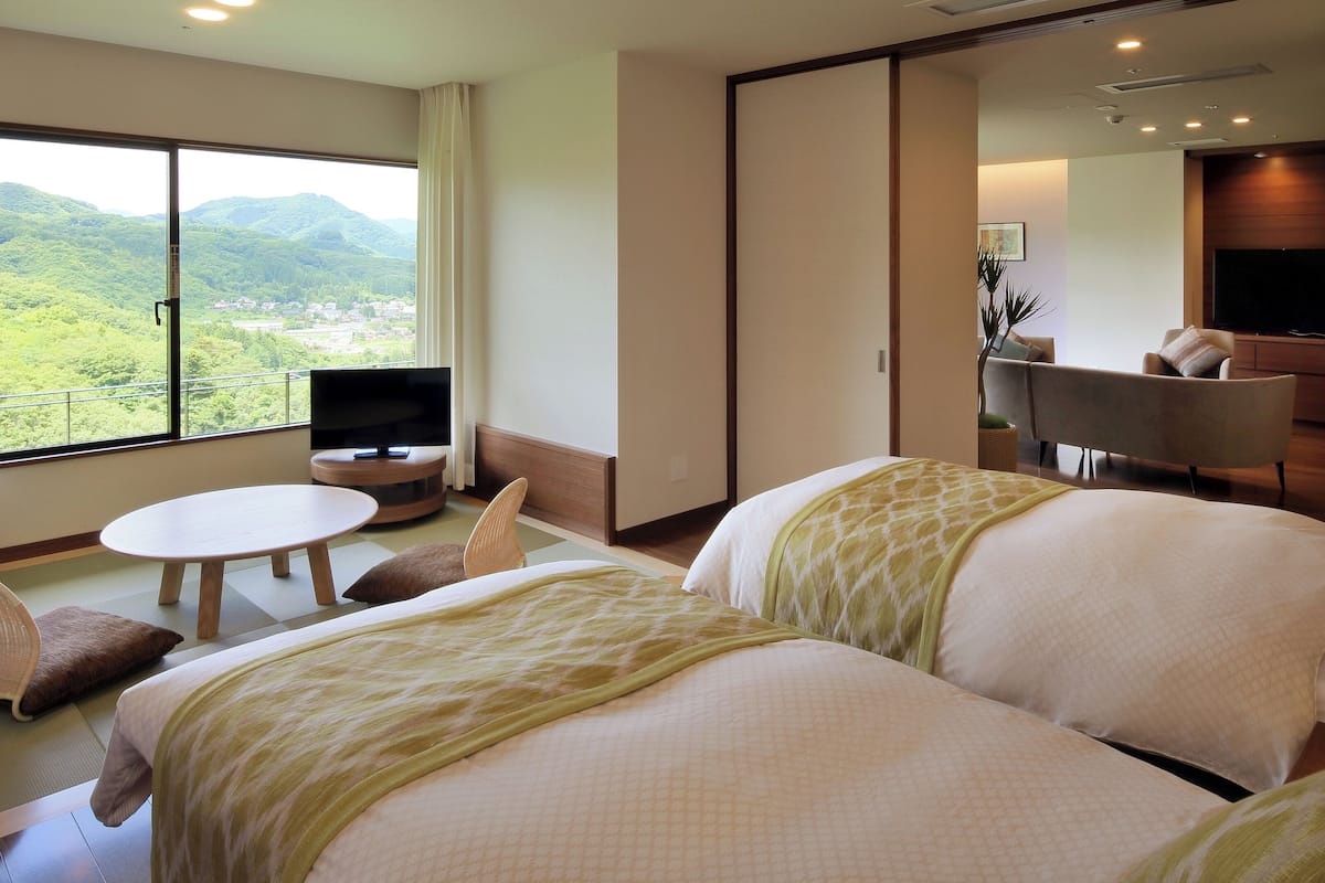 Habitación de hotel con dos camas, televisión, una mesita y un sofá.