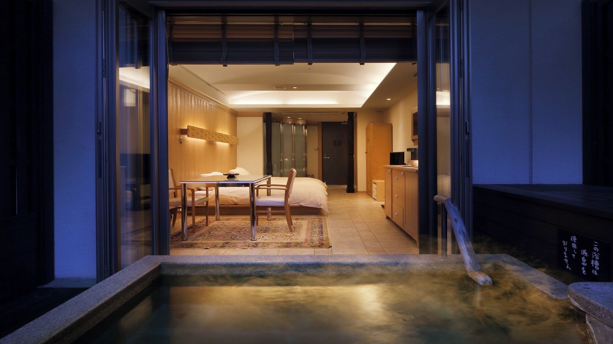 A modern hotel room with a dining area, a bed, and a small pool.
