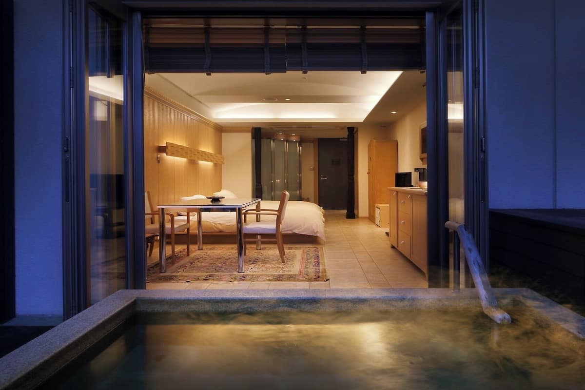 Una habitación de hotel moderna con comedor, cama y una pequeña piscina.