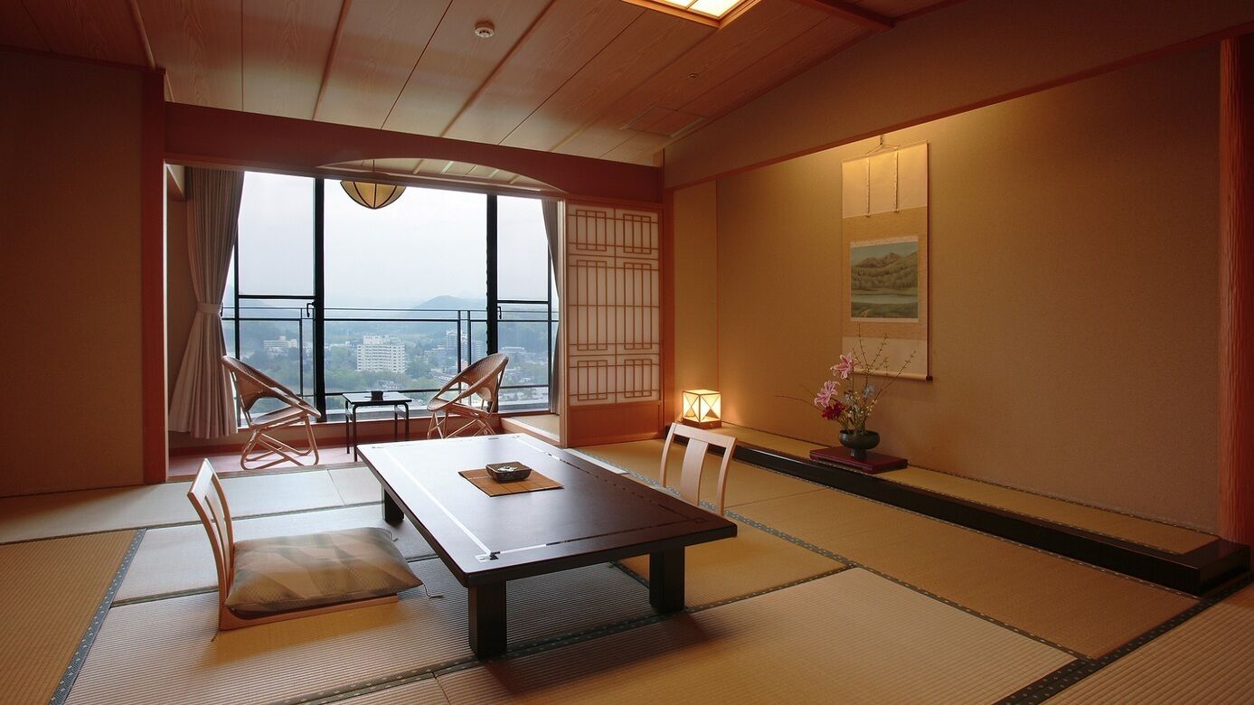 Una habitación japonesa tradicional con suelo de tatami, una mesa baja y vistas a la ciudad.