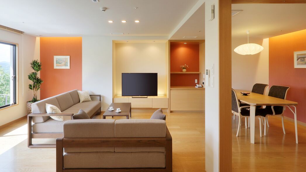 A modern living room with a sofa, TV, dining table, and chairs.