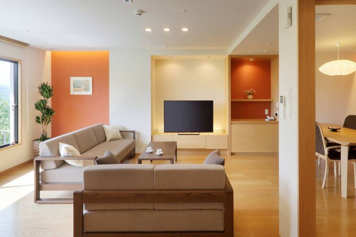 Una sala de estar moderna con un sofá, televisión, mesa de comedor y sillas.