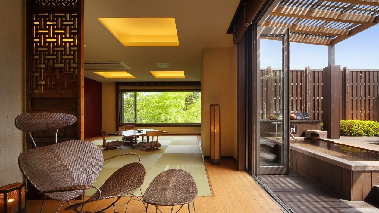 Un interior moderno con comedor, ventanas amplias y vistas a la vegetación.