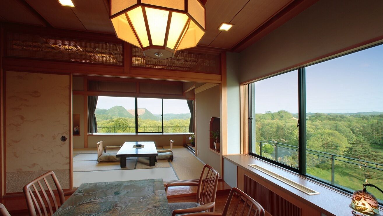 Una habitación con una mesa de comedor, sillas, un ventanal con vistas a zonas verdes y colinas, y una lámpara de techo de estilo tradicional.