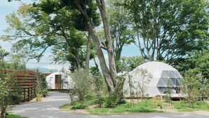 A modern, dome-shaped building surrounded by trees and a gravel path. - Glanta Glamping Village (Sanda)