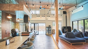 A spacious kitchen with modern appliances, a dining area with a long table and chairs, and a cozy seating area with a sofa. - Orando no Nikai (Aridagawa)