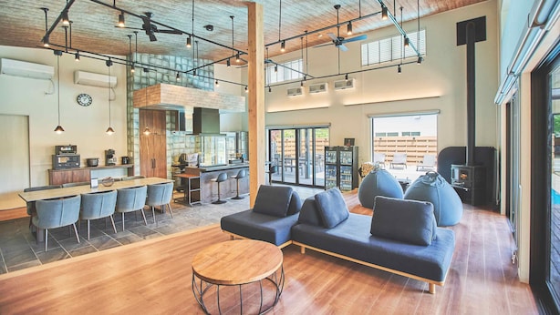 A spacious living area with a wooden dining table, sofas, and a kitchen in the background. - Orando no Nikai (Aridagawa)