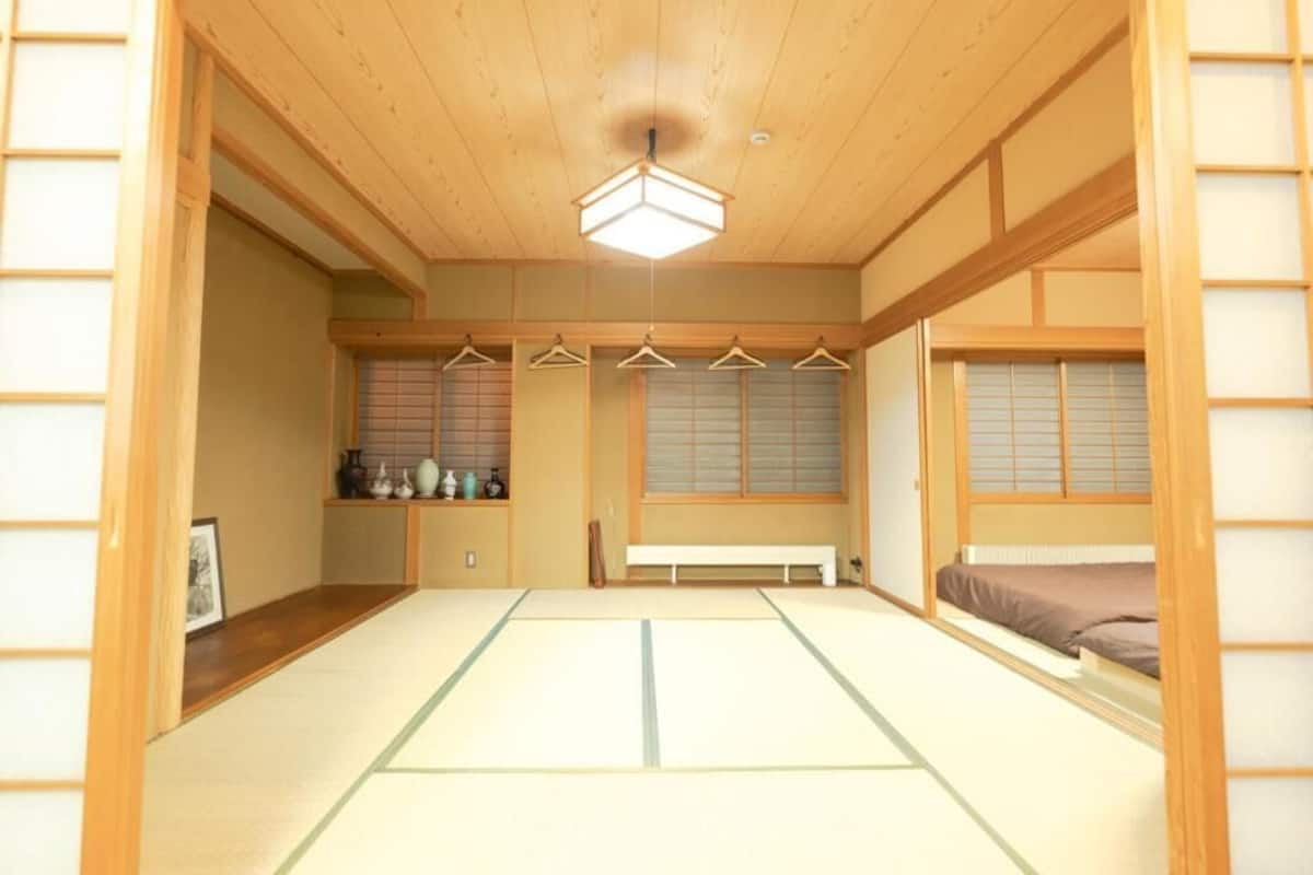 Ein traditioneller japanischer Raum mit Tatami-Boden, einer niedrigen Holzbalkendecke und Shoji-Schirmwänden.