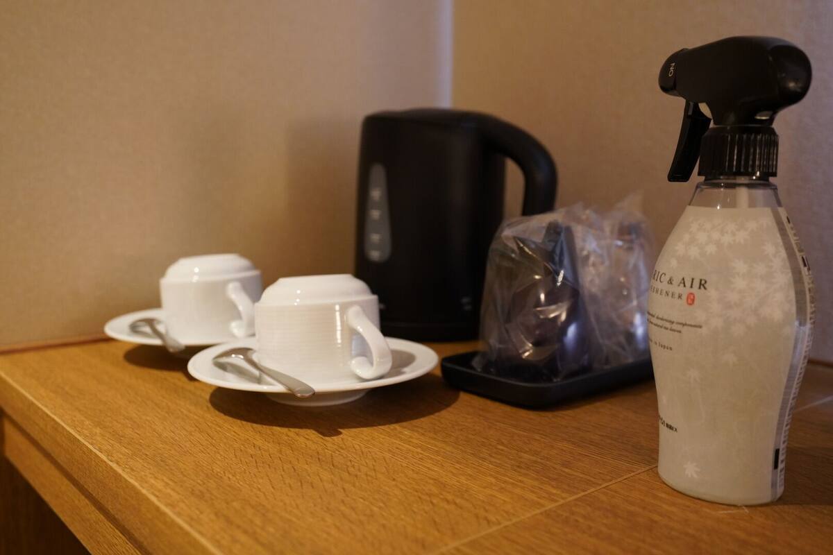 Ett bord med vita koppar och fat, en svart vattenkokare och en sprayflaska med etiketten ”AIR & AIR”.