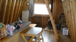 A compact kitchen with a wooden table, a sink, and a stove. - Niseko Shirokuma Cottage (Niseko)