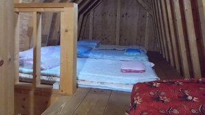 A small, wooden attic bedroom with a sloped ceiling, a single bed with pillows, and a wooden ladder. - Niseko Shirokuma Cottage (Niseko)