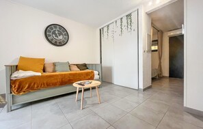 A modern living room with a sofa, a small round table, and a wall clock. - Appt proche Arles et Camargue (Arles)