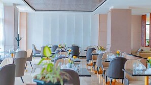A modern dining area with glass tables and chairs, a neutral color scheme, and a clean, minimalist design. - M Hotel Kigali (Kigali)