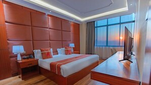 A hotel room with a large bed, a desk, a TV, and a window with a view. - M Hotel Kigali (Kigali)
