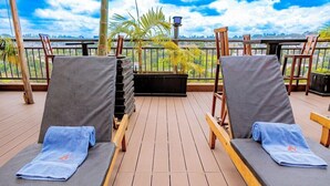 A deck with two lounge chairs, a black planter, and a view of the city. - M Hotel Kigali (Kigali)