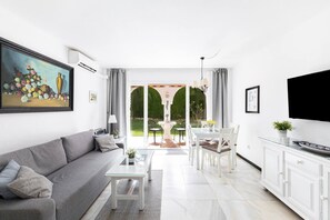 A modern living room with a sofa, coffee table, dining area, and TV. - Apartment Rio Marinas - 1 bedroom - by the beach (Nerja)