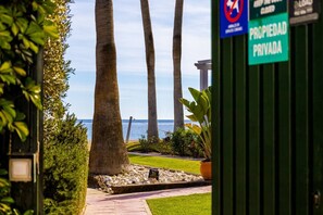 A private property with a view of the sea, palm trees, and a pathway leading to a beach. - Apartment Rio Marinas - 1 bedroom - by the beach (Nerja)