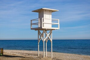 A white lifeguard tower on a pebbled beach with a clear blue sky and calm sea. - Apartment Rio Marinas - 1 bedroom - by the beach (Nerja)