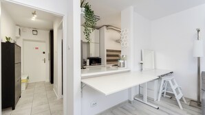 Eine moderne Küche mit weißen Schränken, einer weißen Arbeitsplatte und einem Edelstahl-Spülbecken. In der Ecke steht ein weißer Hocker und ein weißes Schrank.