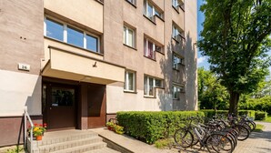 Ein mehrstöckiges Gebäude mit brauner Fassade, Stufen, die zum Eingang führen, und eine Reihe Fahrräder, die davor abgestellt sind.
