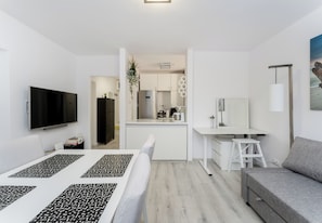 A modern, compact living space with a flat-screen TV, a kitchenette, a dining area, and a seating area. - Azory by Park 2-Bedroom Apartment (Kraków)