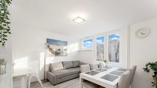 Ein modernes Wohnzimmer mit einer Couch, einem Esstisch und einem Bild an der Wand.
