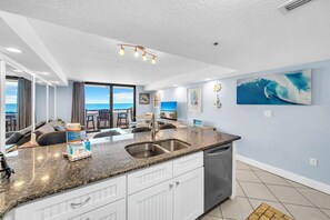 A modern kitchen with granite countertops, white cabinetry, and a large window overlooking the ocean. - Gulf Front-Heart of Destin-Lots of Amenities! Sundestin 209 (Destin)