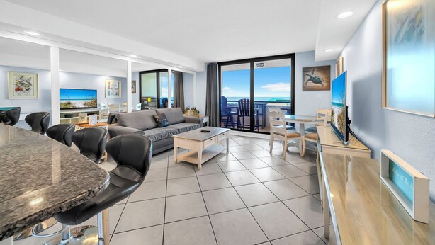 Een moderne woonkamer met een bank, salontafel, eethoek en een groot raam met uitzicht.