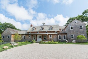 A large, two-story wooden house with a gravel driveway and outdoor seating. - Quiet, private East Hampton home with pool close to Round Swamp (East Hampton)