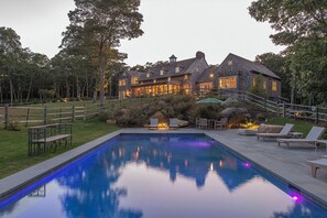 Un'ampia casa con piscina, mobili da esterno e un giardino curato.