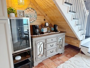 Eine Küche mit Holzboden, einer Kaffeestation und Blick auf eine Treppe.