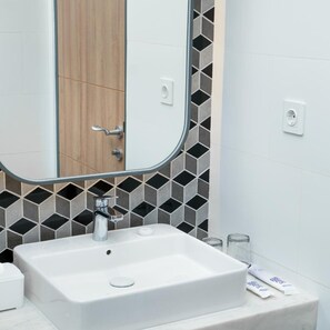A bathroom with a white sink, a mirror, and a door. - Fox Lite Hotel Samarinda (Samarinda)