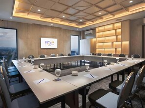 Una sala conferenze con un lungo tavolo, sedie e uno schermo che mostra 'FOX'.
