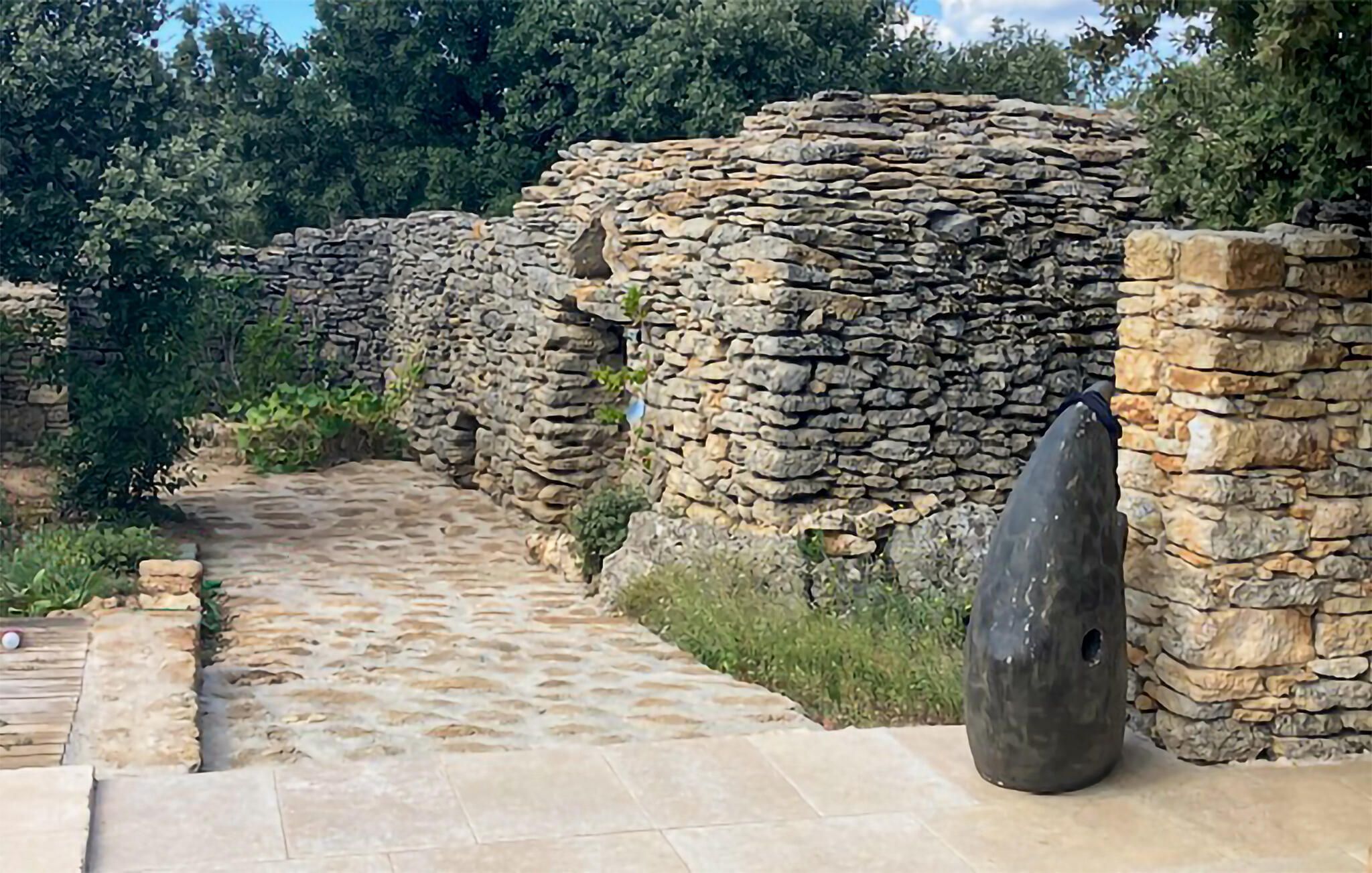 A stone pathway leading to a stone wall with a large, flat stone slab on the right.