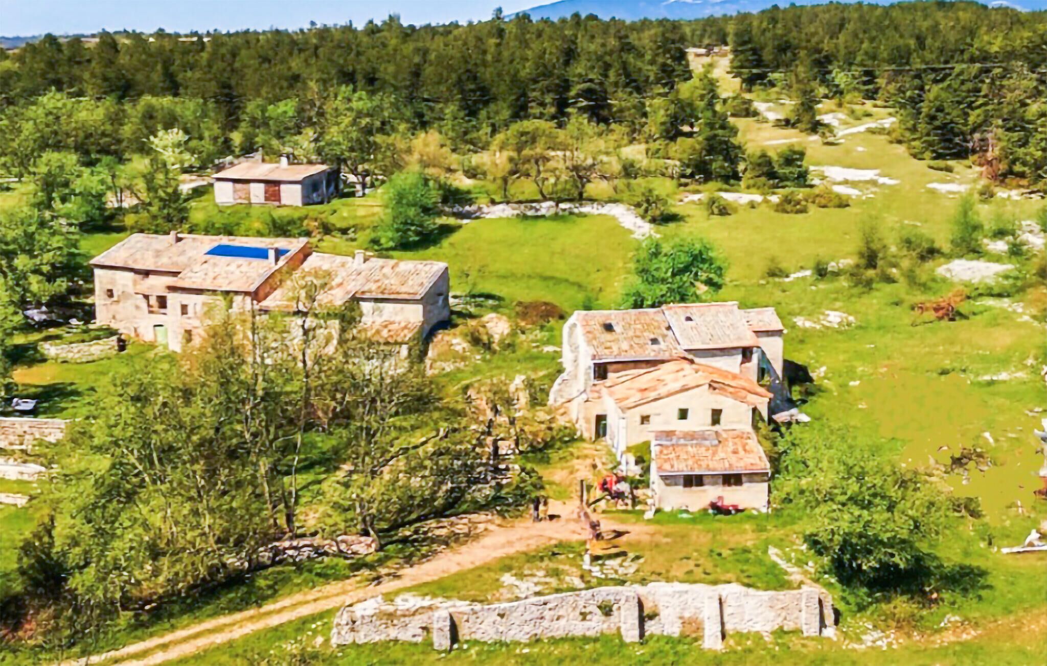 Entorno rural con edificios de piedra, cielo despejado y un camino que atraviesa el paisaje.