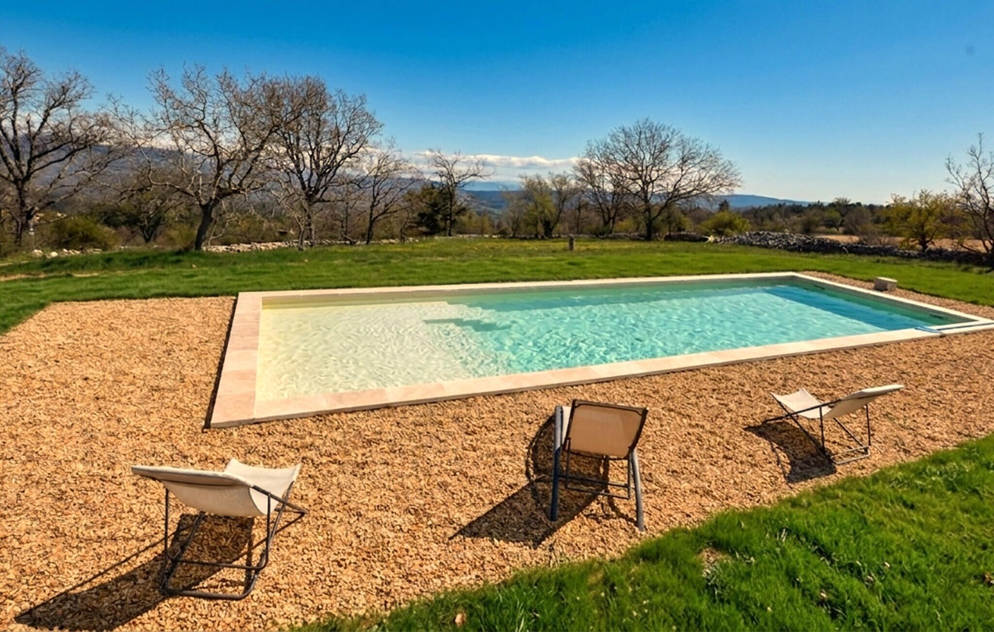 Una piscina rettangolare con acqua cristallina, circondata da un solarium in legno.