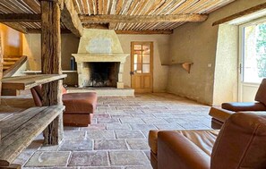Ein rustikales Interieur mit Kamin aus Stein, Holzbalken und Ledersitzmöbeln.