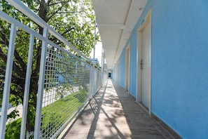 Un pasillo con valla metálica, paredes azules y suelo de baldosas.