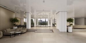 Un vestíbulo amplio con diseño moderno, que incluye una zona de estar con sofás y una mesa de centro, una escalera y grandes ventanales con vistas al exterior.