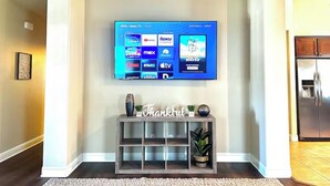 A flat-screen TV mounted on a wall displaying various streaming services. - The home away from home! (Bakersfield)