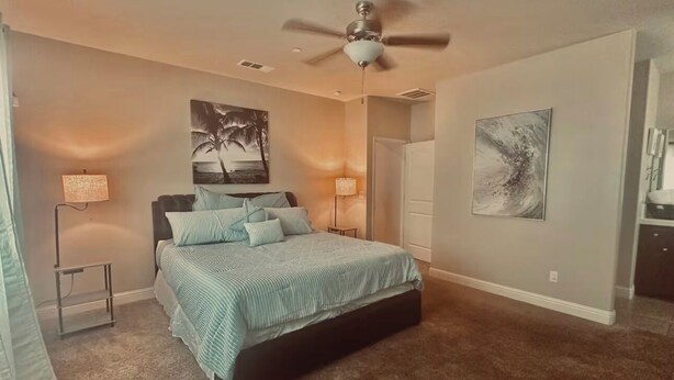 A bedroom with a bed, a ceiling fan, two wall-mounted lamps, and a door. - The home away from home! (Bakersfield)
