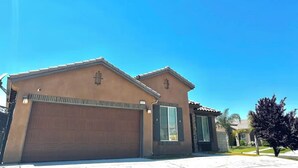 A two-story house with a garage, a small porch, and a clear blue sky. - The home away from home! (Bakersfield)