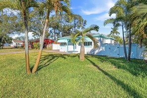 A house with a white exterior and blue trim, surrounded by a well-maintained lawn and palm trees. - SALTAIRE RETREAT ST PETE  (St. Petersburg)