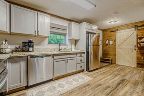 A modern kitchen with stainless steel appliances, white cabinetry, and a wooden floor. - NEW Hot Tub • 2 Mi to Parkway • Fire Pit • Arcade (Sevier County)