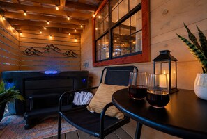 An outdoor seating area with a black sofa, a chair, a table with glasses and a candle, and a potted plant. - NEW Hot Tub • 2 Mi to Parkway • Fire Pit • Arcade (Sevier County)