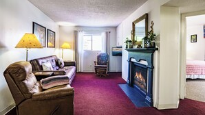 A living room with a fireplace, a sofa, a chair, and a bed. - King 1BR Retreat, Jetted Bathtub, Indoor + Outdoor Pool, Walk to Parkway (Gatlinburg)