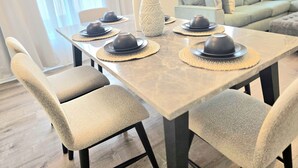 Een eettafel met vier stoelen, een vaas en een decoratief wandobject.