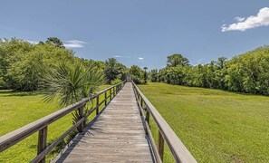 Une promenade en bois qui s’étend à travers une zone herbeuse, avec des arbres de chaque côté.