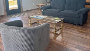 Una sala de estar con un sofá, un sillón, una mesita de centro y una escalera.